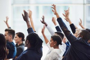 Group of businesspeople raising hands during a discussion on questions to ask when buying a business.