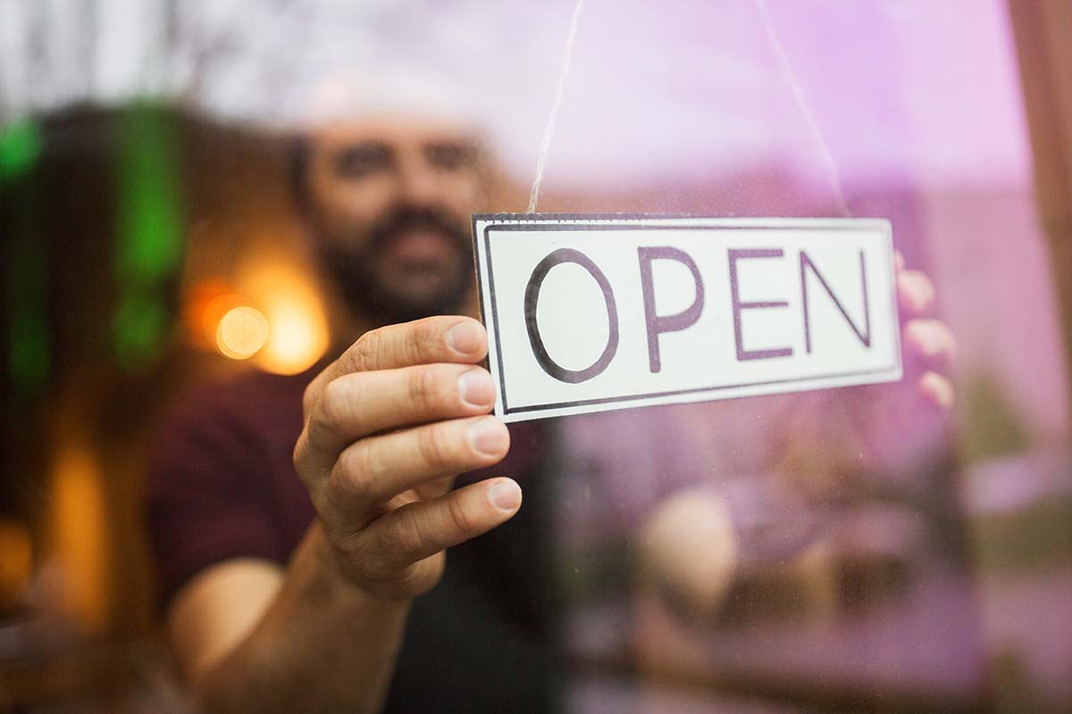 Business owner opening their store, representing starting a business journey as part of the selling a business checklist.
