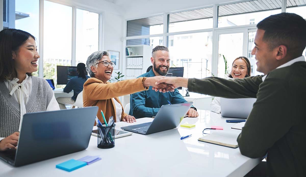 Group of professionals shaking hands after a meeting, sealing the deal to buy an existing business.