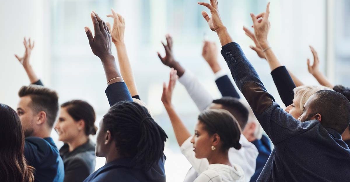 Group of businesspeople raising hands during a discussion on questions to ask when buying a business.